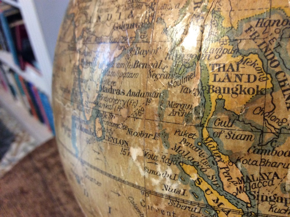 A printed paper terrestrial globe mounted on an ornate cast iron tripod base with a metal semi-meridian arm. View XIII