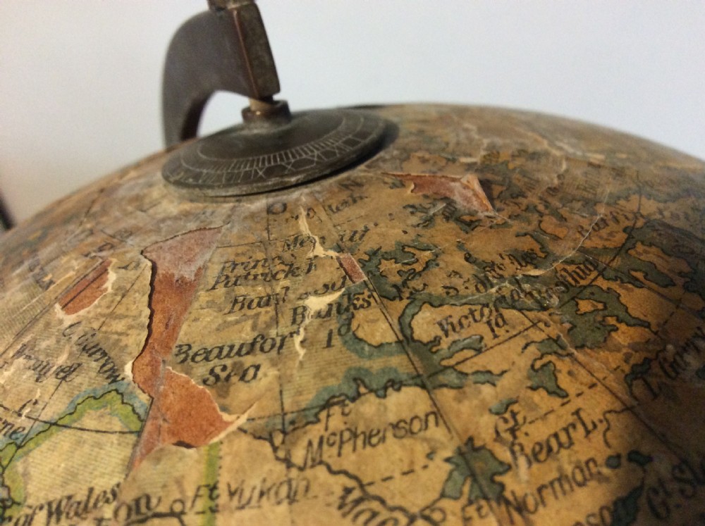 A printed paper terrestrial globe mounted on an ornate cast iron tripod base with a metal semi-meridian arm. View XIV