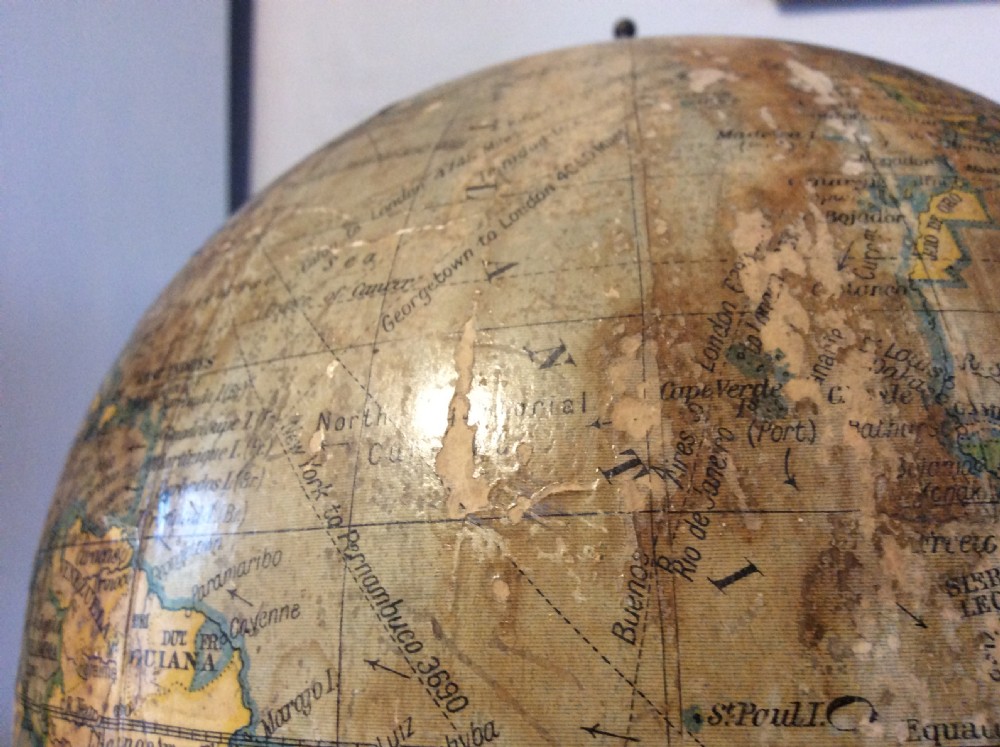 A printed paper terrestrial globe mounted on an ornate cast iron tripod base with a metal semi-meridian arm. View XV