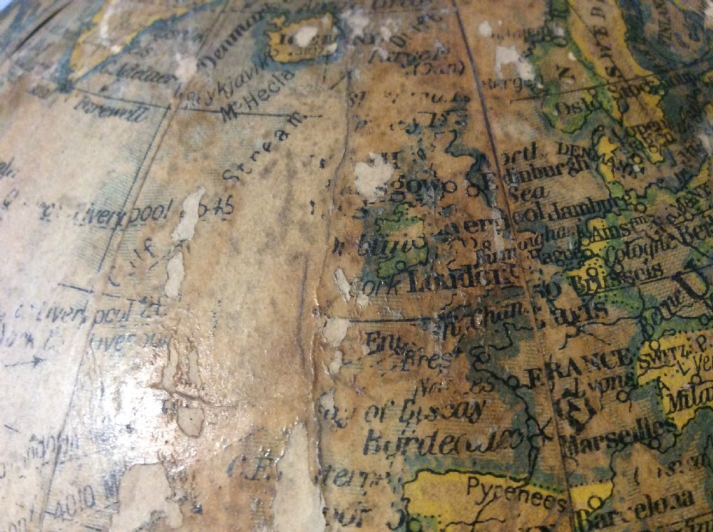 A printed paper terrestrial globe mounted on an ornate cast iron tripod base with a metal semi-meridian arm. View XVI