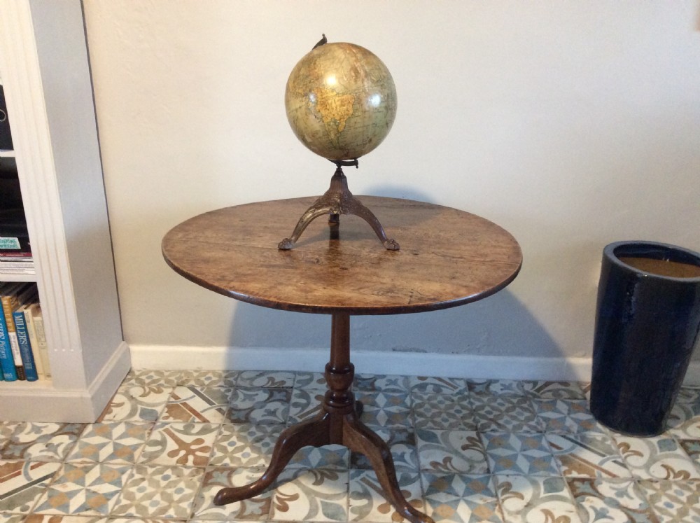 A printed paper terrestrial globe mounted on an ornate cast iron tripod base with a metal semi-meridian arm. View XVII