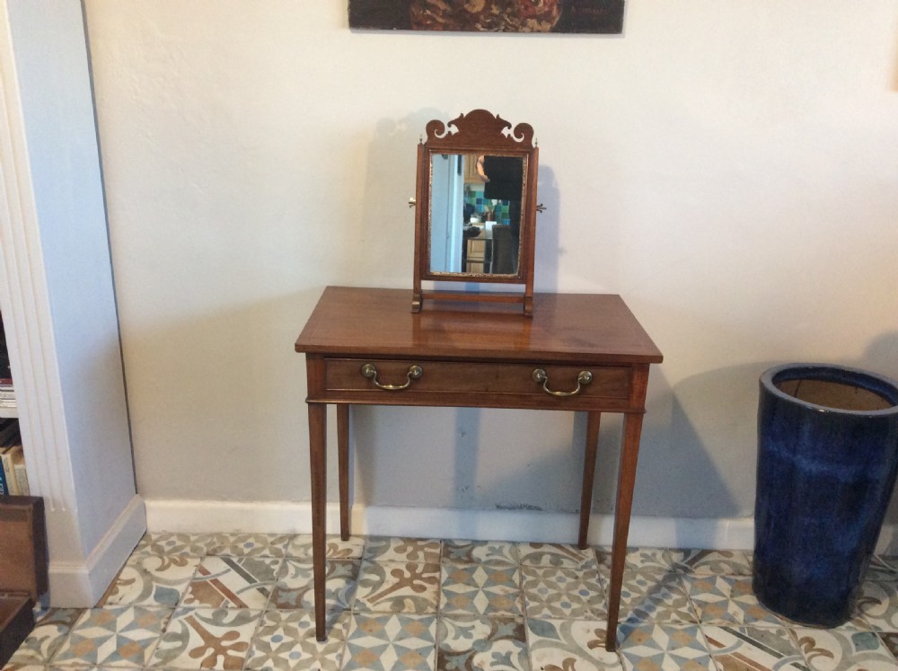 A Georgian dark mahogany skeleton toilet mirror featuring a scroll-carved cresting, rectangular pivoting mirror, side brass fixings, and trestle feet. View II