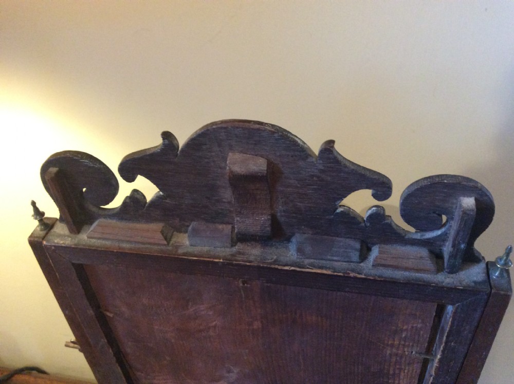 A Georgian dark mahogany skeleton toilet mirror featuring a scroll-carved cresting, rectangular pivoting mirror, side brass fixings, and trestle feet. View IX
