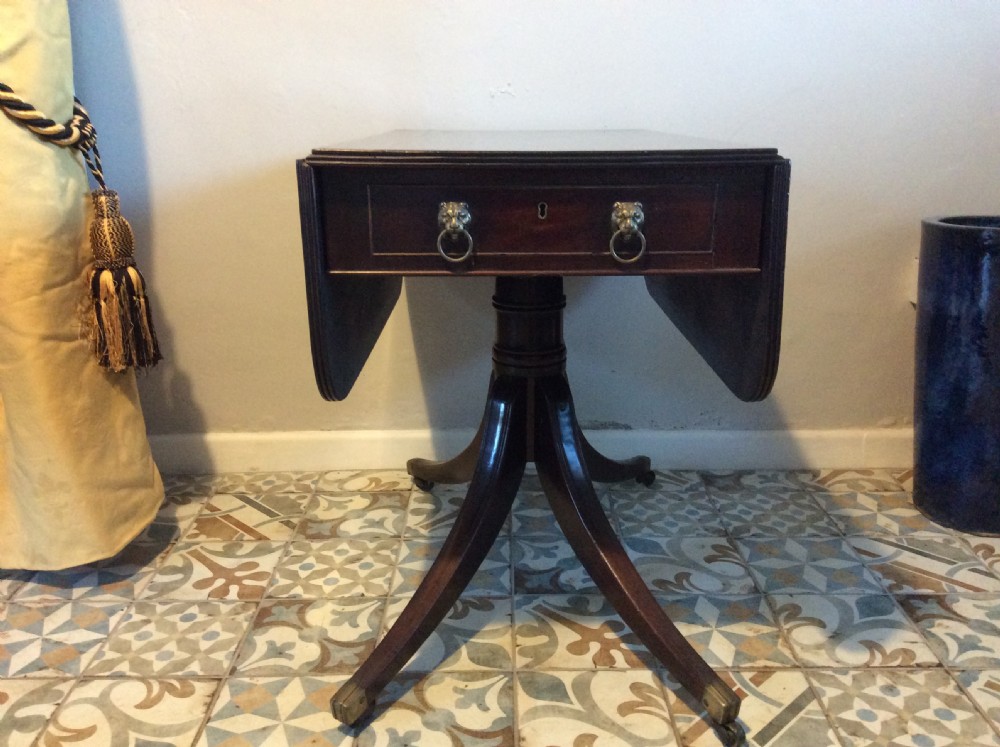 A Georgian mahogany drop-leaf hall table with two hinged side flaps, supported by a central pedestal and four curved splayed legs with brass castors. View III