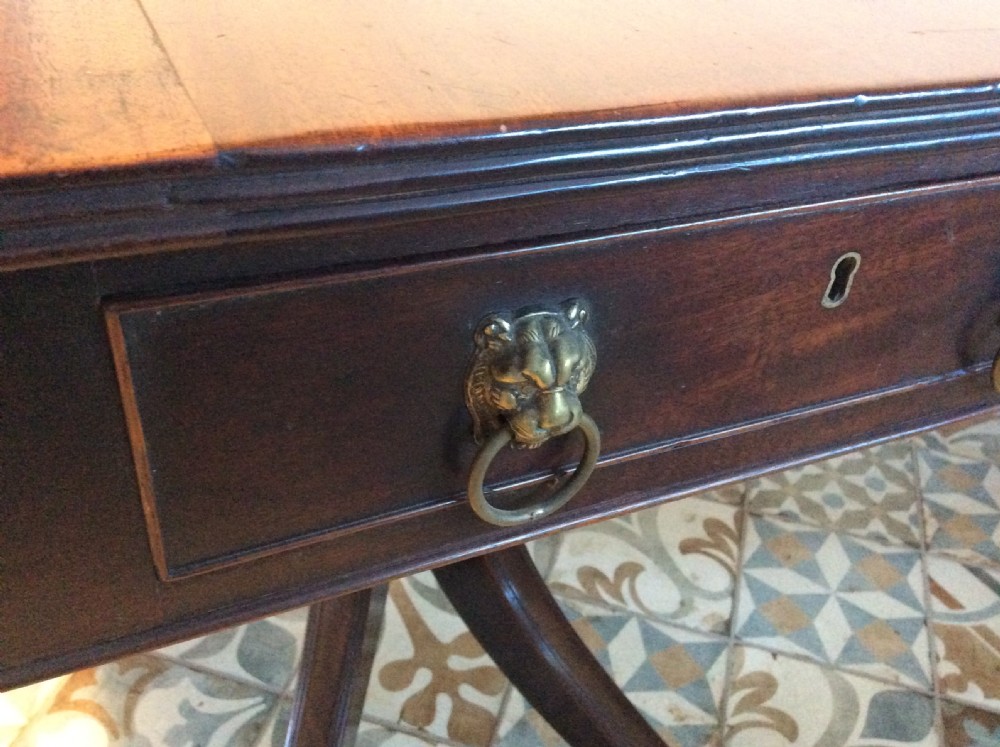 A Georgian mahogany drop-leaf hall table with two hinged side flaps, supported by a central pedestal and four curved splayed legs with brass castors. View VI