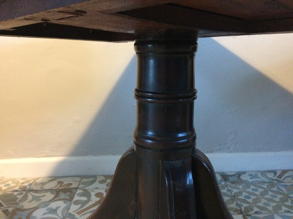 A Georgian mahogany drop-leaf hall table with two hinged side flaps, supported by a central pedestal and four curved splayed legs with brass castors. View VIII