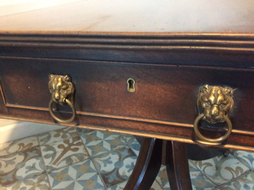 A Georgian mahogany drop-leaf hall table with two hinged side flaps, supported by a central pedestal and four curved splayed legs with brass castors. View IX
