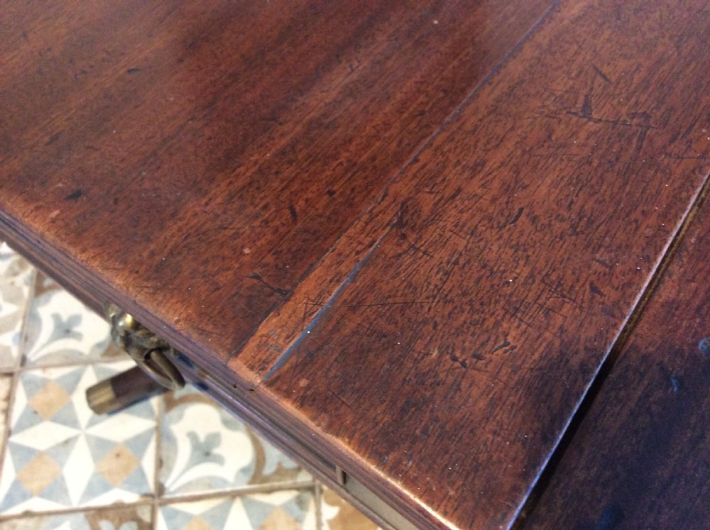 A Georgian mahogany drop-leaf hall table with two hinged side flaps, supported by a central pedestal and four curved splayed legs with brass castors. View XII