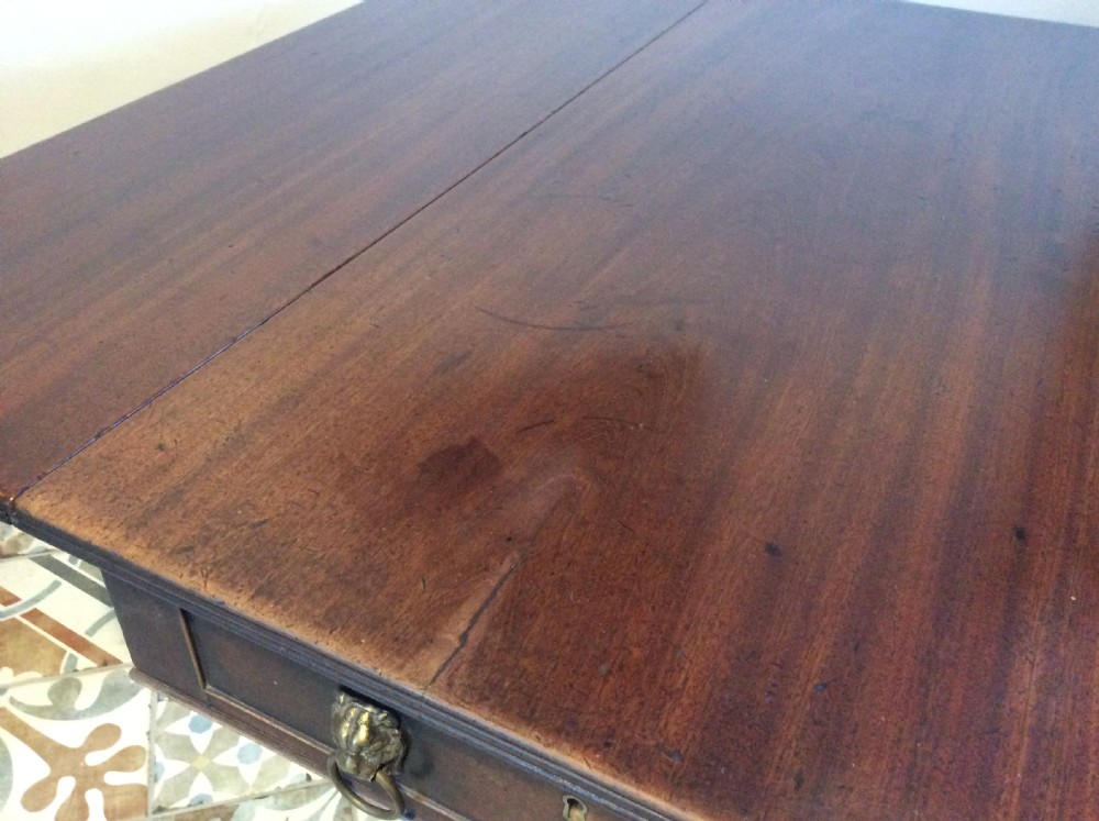 A Georgian mahogany drop-leaf hall table with two hinged side flaps, supported by a central pedestal and four curved splayed legs with brass castors. View XIII