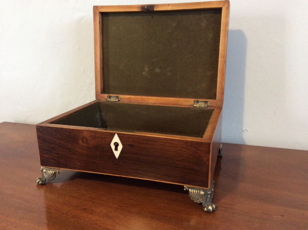 An open rectangular dark rosewood jewellery box featuring a diamond-shaped bone escutcheon, brass claw feet, and a dark lined interior.