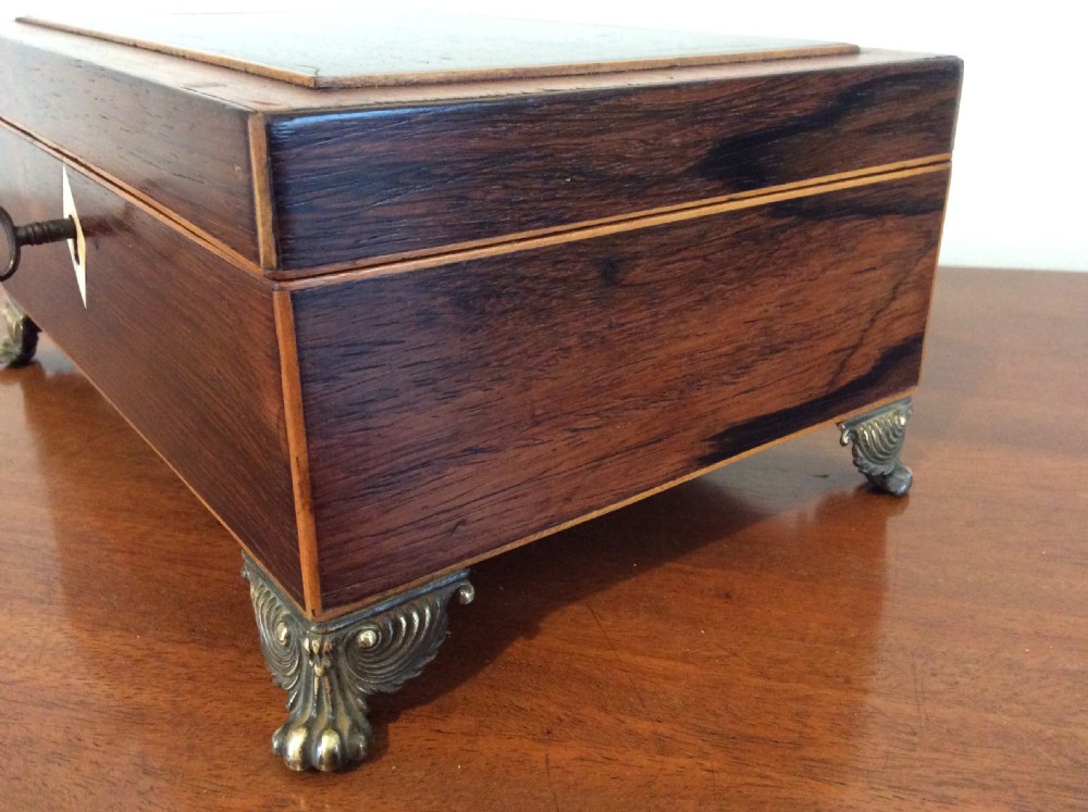 An open rectangular dark rosewood jewellery box featuring a diamond-shaped bone escutcheon, brass claw feet, and a dark lined interior. View V