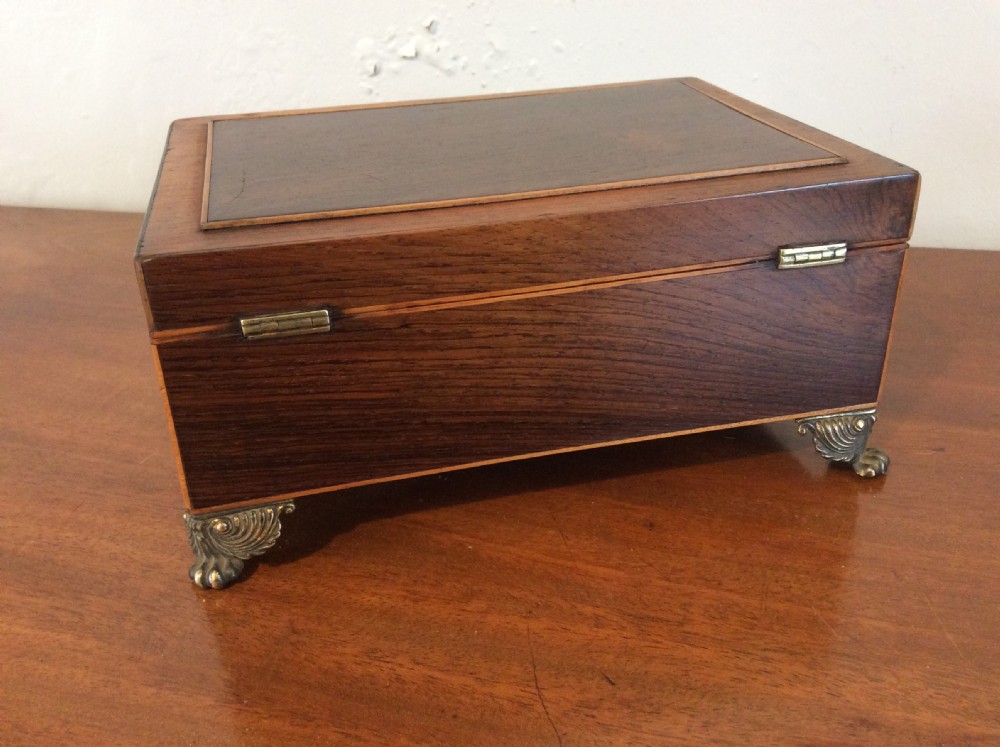 An open rectangular dark rosewood jewellery box featuring a diamond-shaped bone escutcheon, brass claw feet, and a dark lined interior. View VI