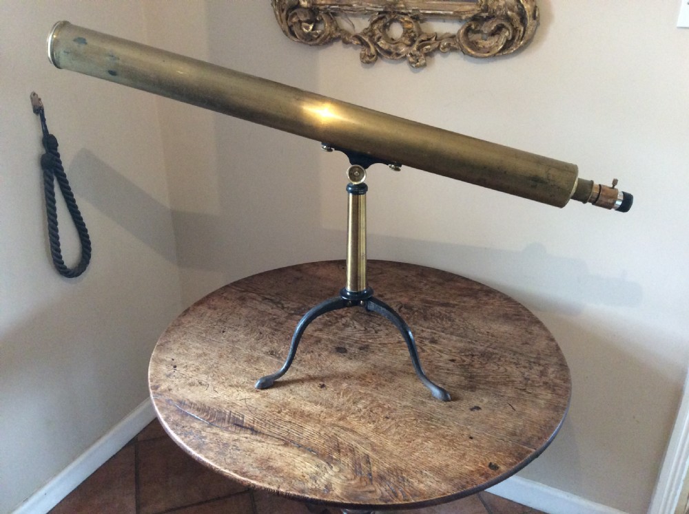 A nineteenth-century brass terrestrial library telescope supported by a dark tripod stand.