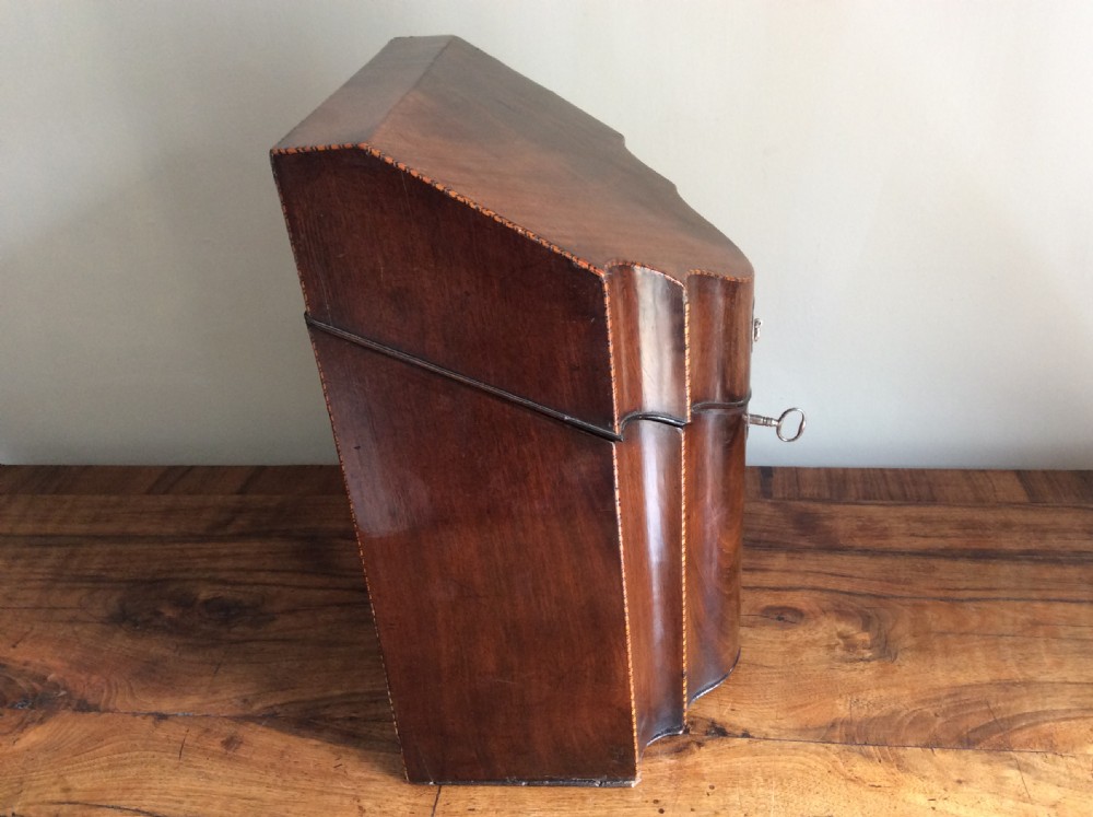 A Georgian mahogany knife box featuring a sloped hinged lid, serpentine front, boxwood stringing, and a metal keyhole escutcheon. View V