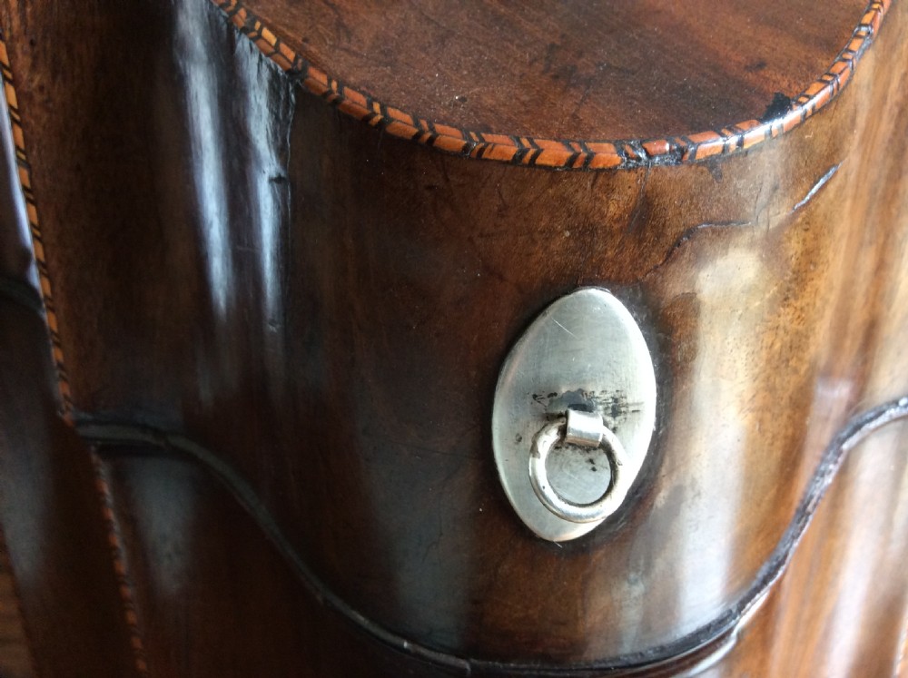 A Georgian mahogany knife box featuring a sloped hinged lid, serpentine front, boxwood stringing, and a metal keyhole escutcheon. View VII