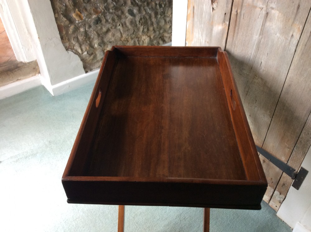 A nineteenth-century mahogany butlers tray featuring raised gallery sides with cut-out handles, resting on a folding X-frame wooden stand. View III