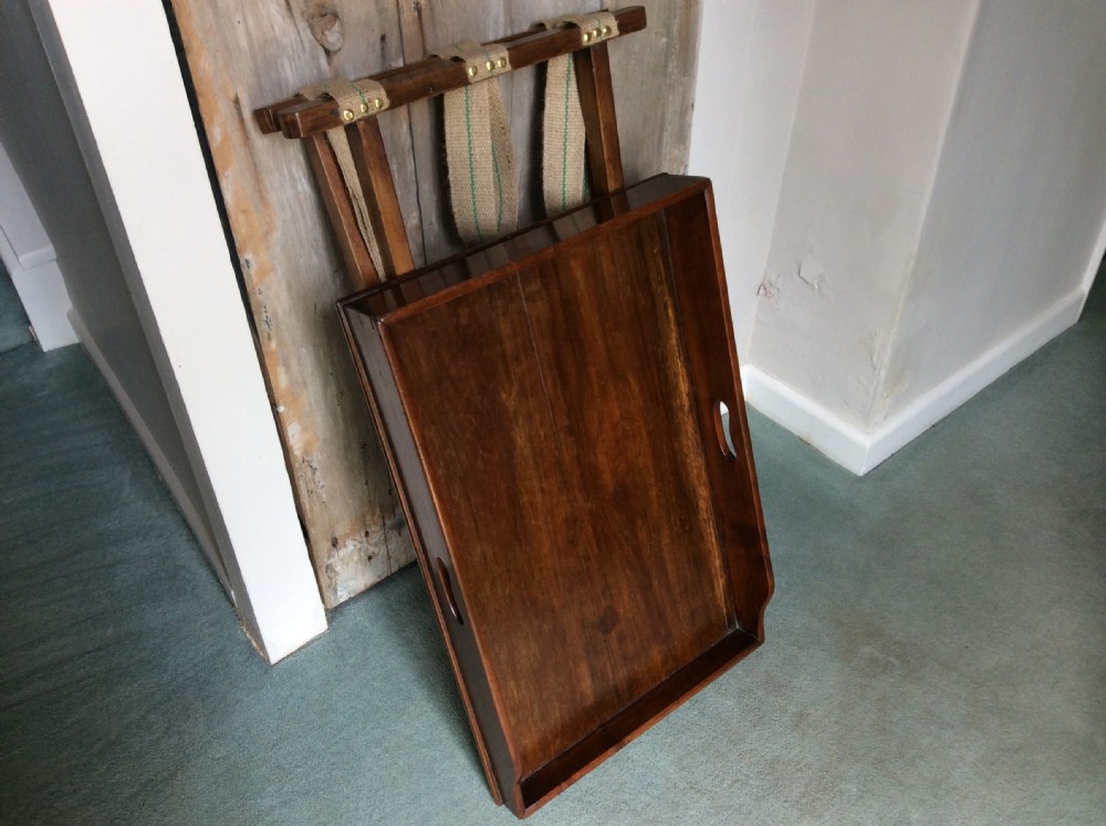 A nineteenth-century mahogany butlers tray featuring raised gallery sides with cut-out handles, resting on a folding X-frame wooden stand. View VII