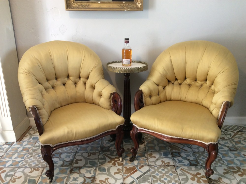A near pair of Victorian button-backed tub armchairs upholstered in yellow fabric with carved mahogany cabriole legs on castors. View II