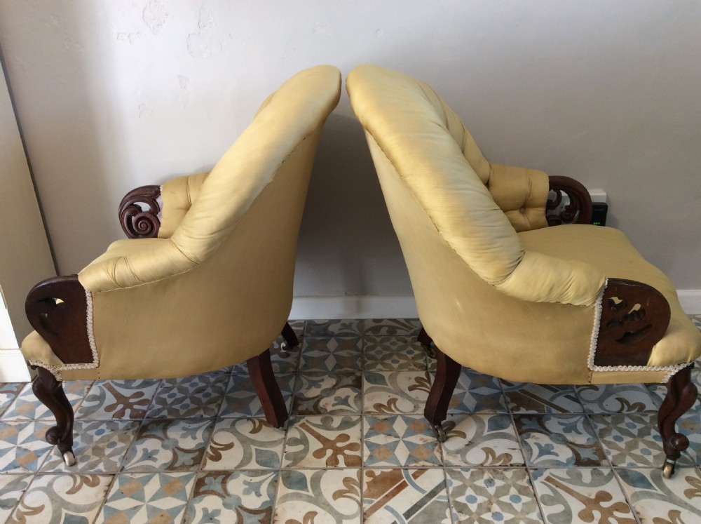 A near pair of Victorian button-backed tub armchairs upholstered in yellow fabric with carved mahogany cabriole legs on castors. View III
