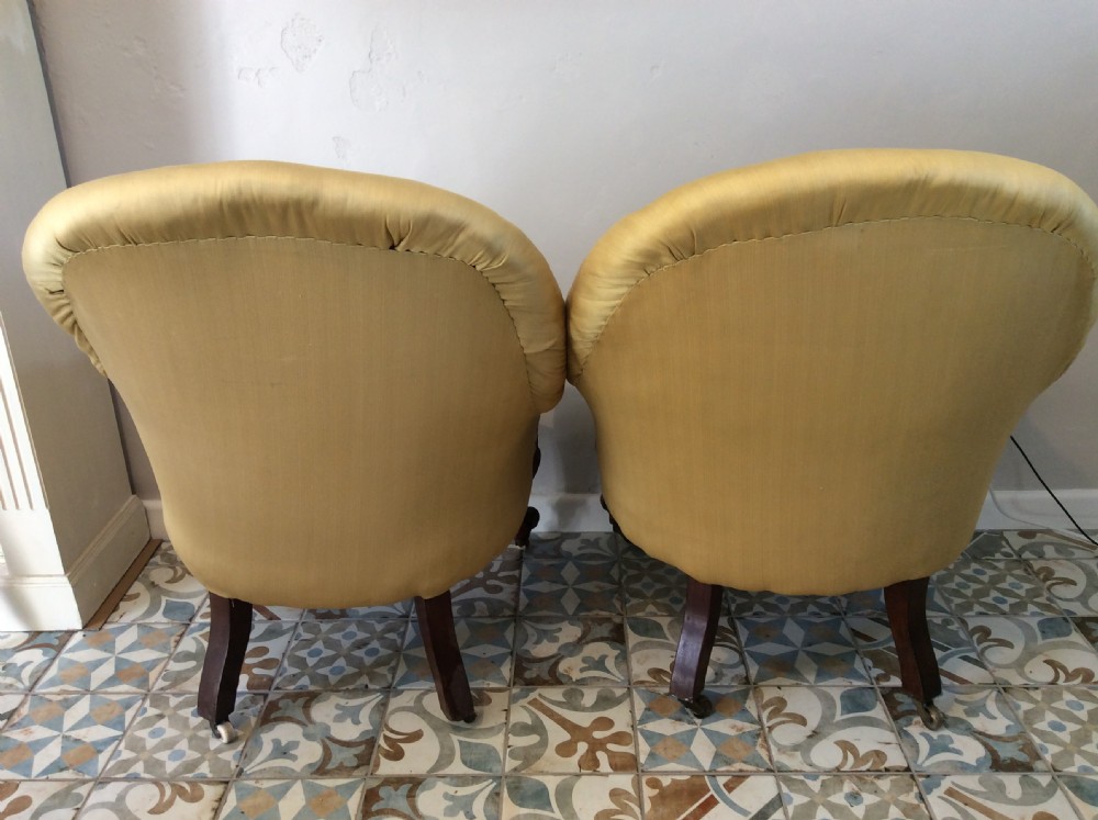 A near pair of Victorian button-backed tub armchairs upholstered in yellow fabric with carved mahogany cabriole legs on castors. View V