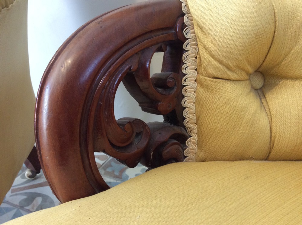 A near pair of Victorian button-backed tub armchairs upholstered in yellow fabric with carved mahogany cabriole legs on castors. View X