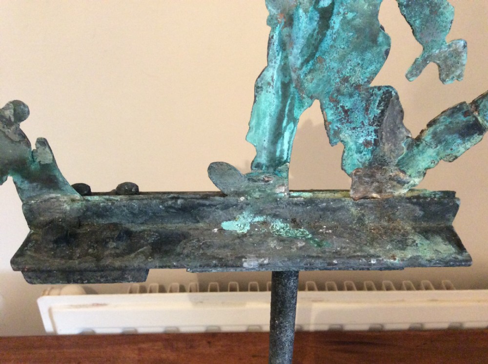 An early 20th-century copper weather vane featuring running figures with a natural verdigris patina, mounted on a stone block stand. View VI