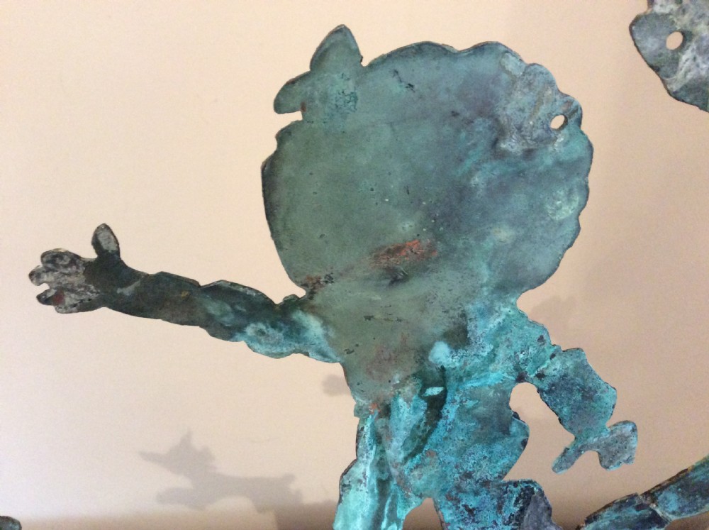 An early 20th-century copper weather vane featuring running figures with a natural verdigris patina, mounted on a stone block stand. View VIII
