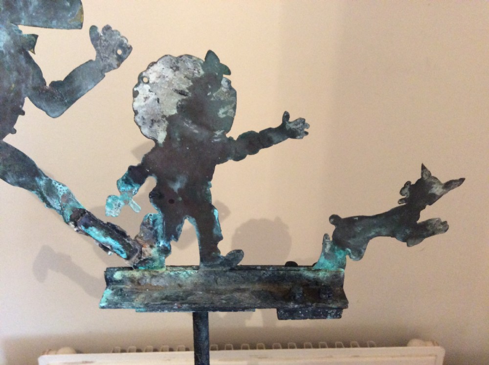 An early 20th-century copper weather vane featuring running figures with a natural verdigris patina, mounted on a stone block stand. View XII