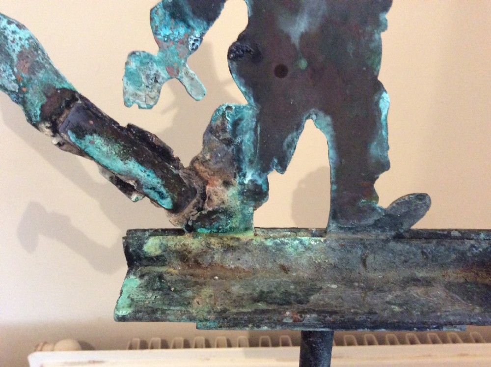 An early 20th-century copper weather vane featuring running figures with a natural verdigris patina, mounted on a stone block stand. View XIV