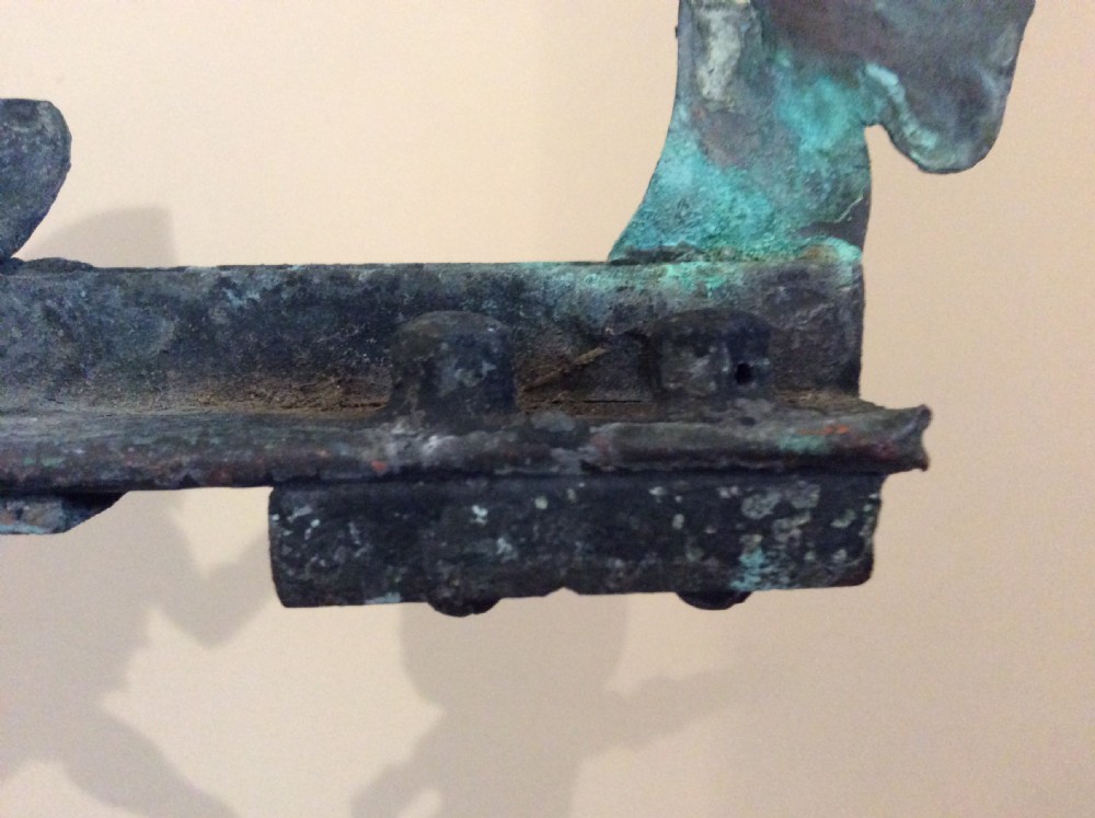 An early 20th-century copper weather vane featuring running figures with a natural verdigris patina, mounted on a stone block stand. View XVII