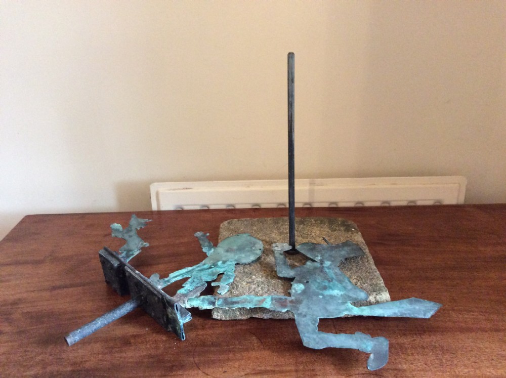 An early 20th-century copper weather vane featuring running figures with a natural verdigris patina, mounted on a stone block stand. View XXII