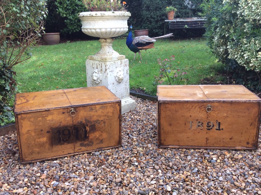 A pair of rectangular Victorian deed boxes finished in warm ochre paint with dark metal edging, ring pull handles, and black stencilled dates reading 1891 and 1911. View II