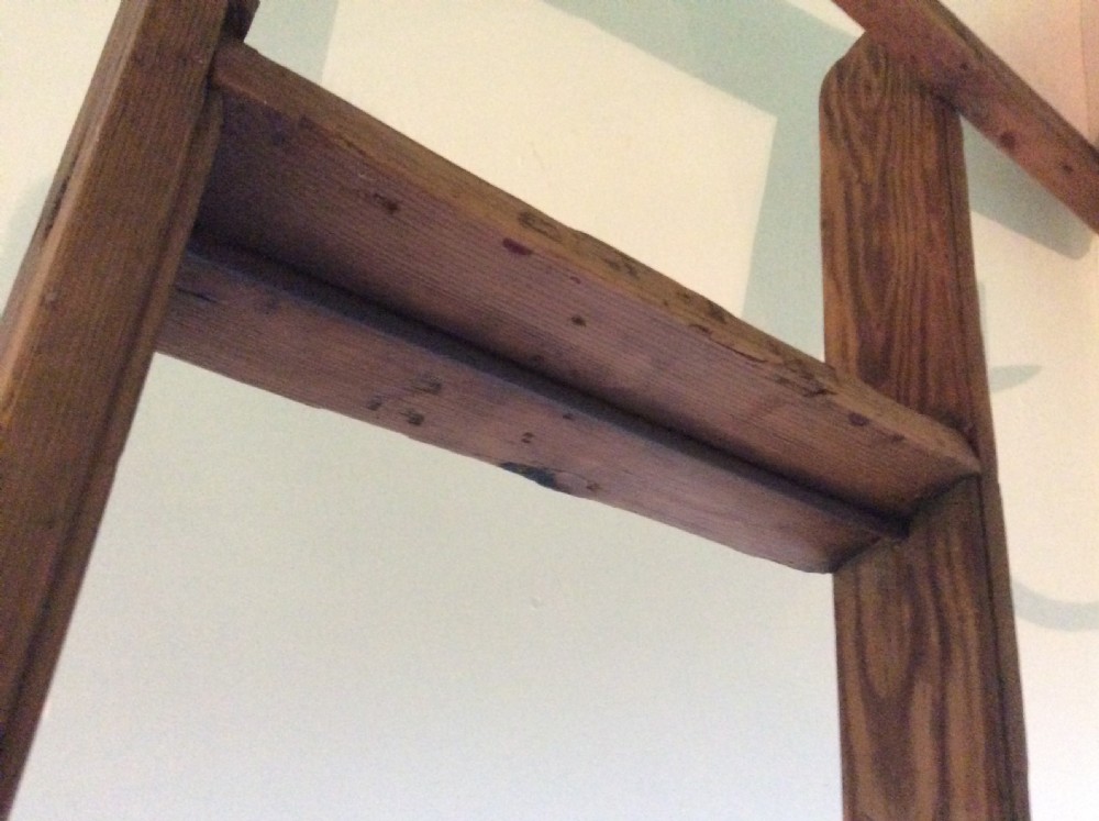 A tall Victorian pine shop ladder featuring straight wooden stiles, flat horizontal rungs, and a top mounting bar. View V