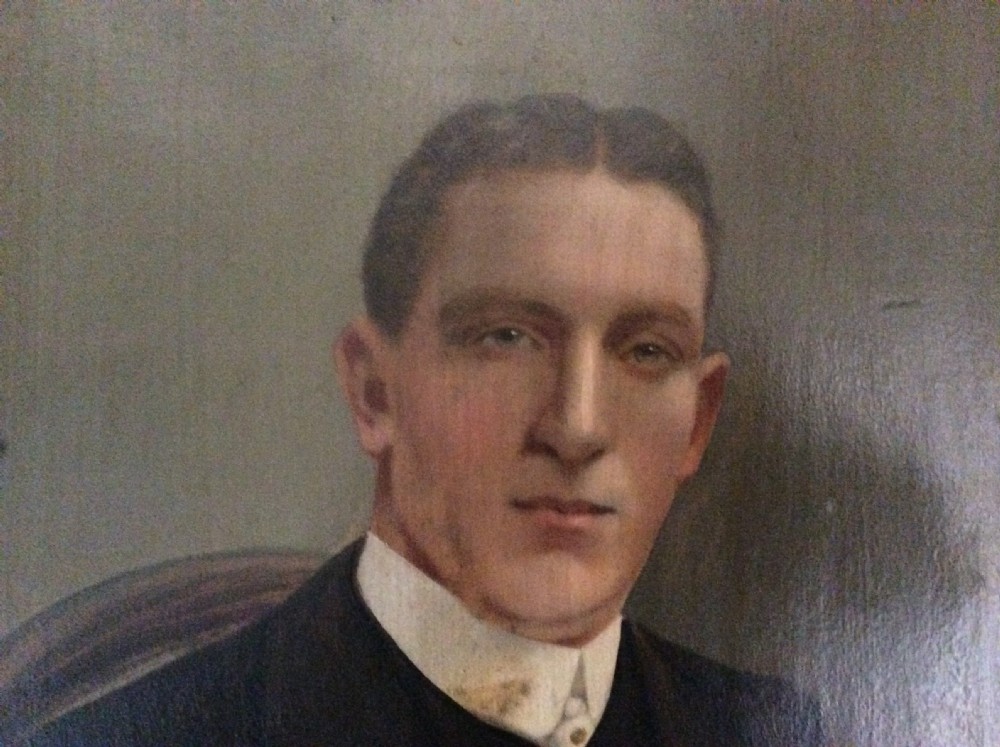 An antique oil painting depicting a seated gentleman in formal dark attire set within a heavily carved gold leaf frame. View III