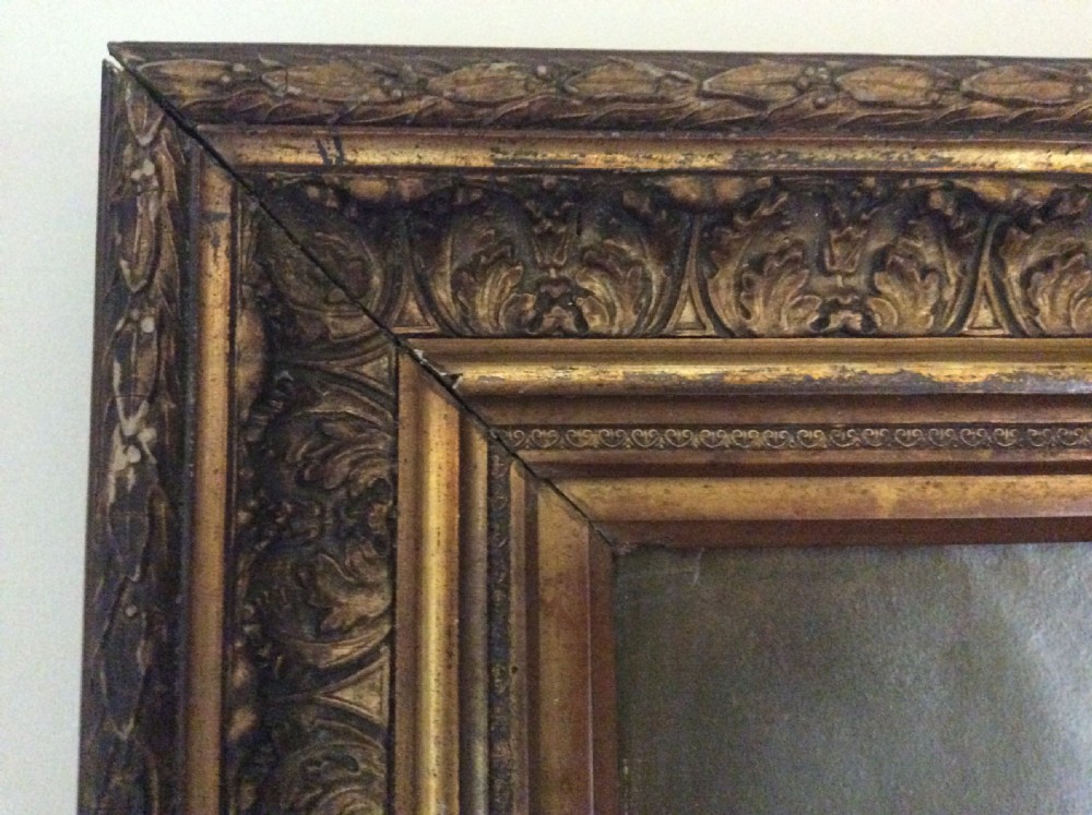 An antique oil painting depicting a seated gentleman in formal dark attire set within a heavily carved gold leaf frame. View VIII
