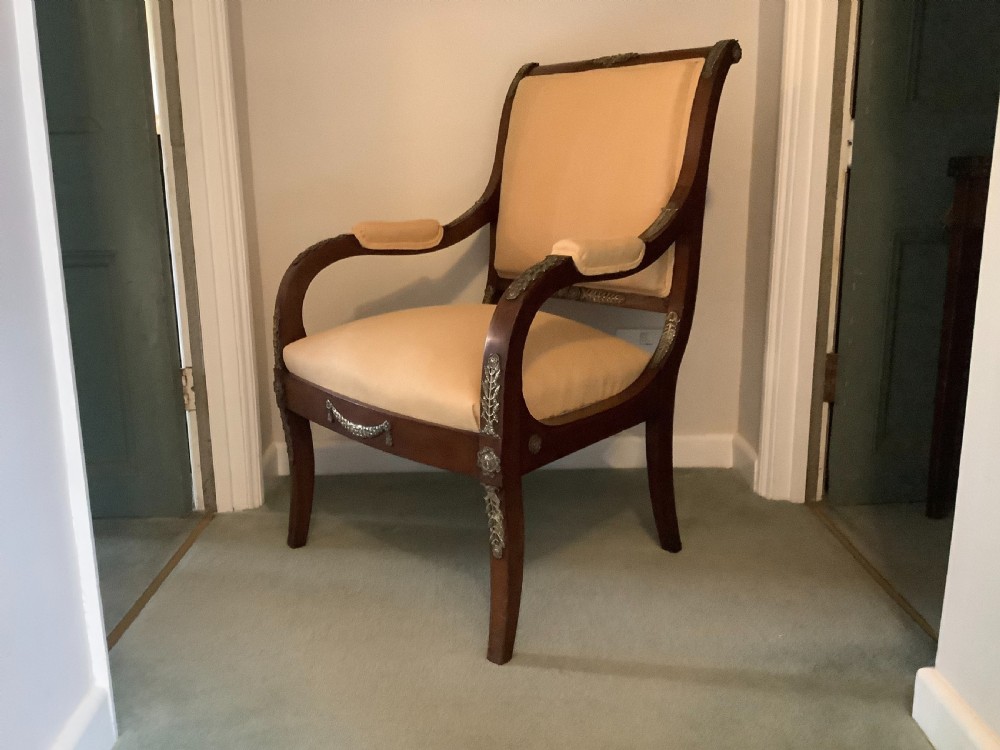 A 19th-century French Empire mahogany open armchair featuring light gold-coloured fabric upholstery and ornate brass leaf mounts. View II