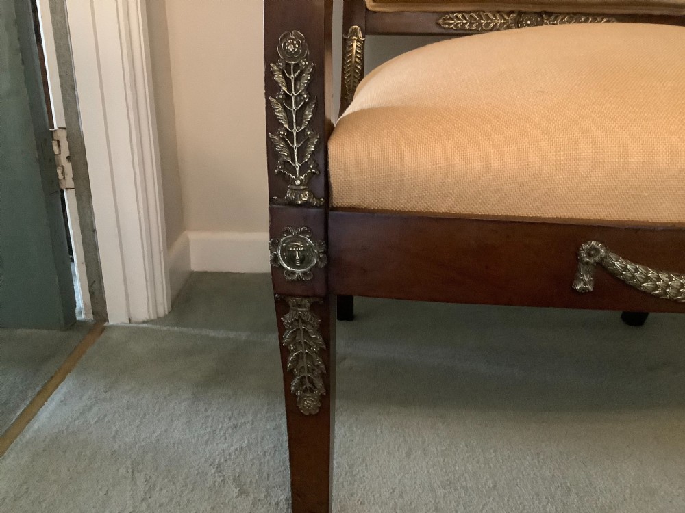 A 19th-century French Empire mahogany open armchair featuring light gold-coloured fabric upholstery and ornate brass leaf mounts. View III