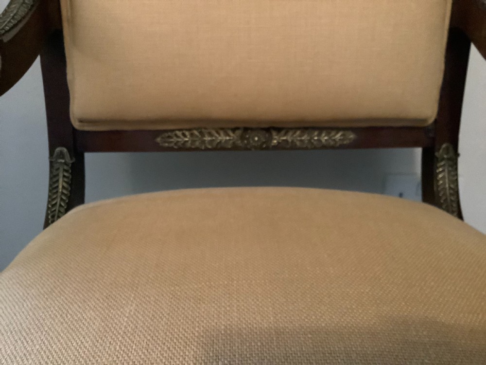 A 19th-century French Empire mahogany open armchair featuring light gold-coloured fabric upholstery and ornate brass leaf mounts. View IX