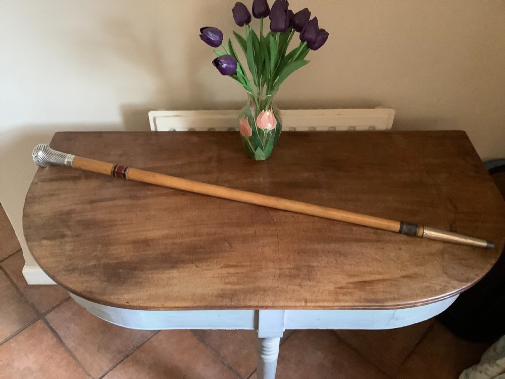 A wooden walking cane featuring a swirl-fluted hallmarked silver pommel top and silver collar. View V