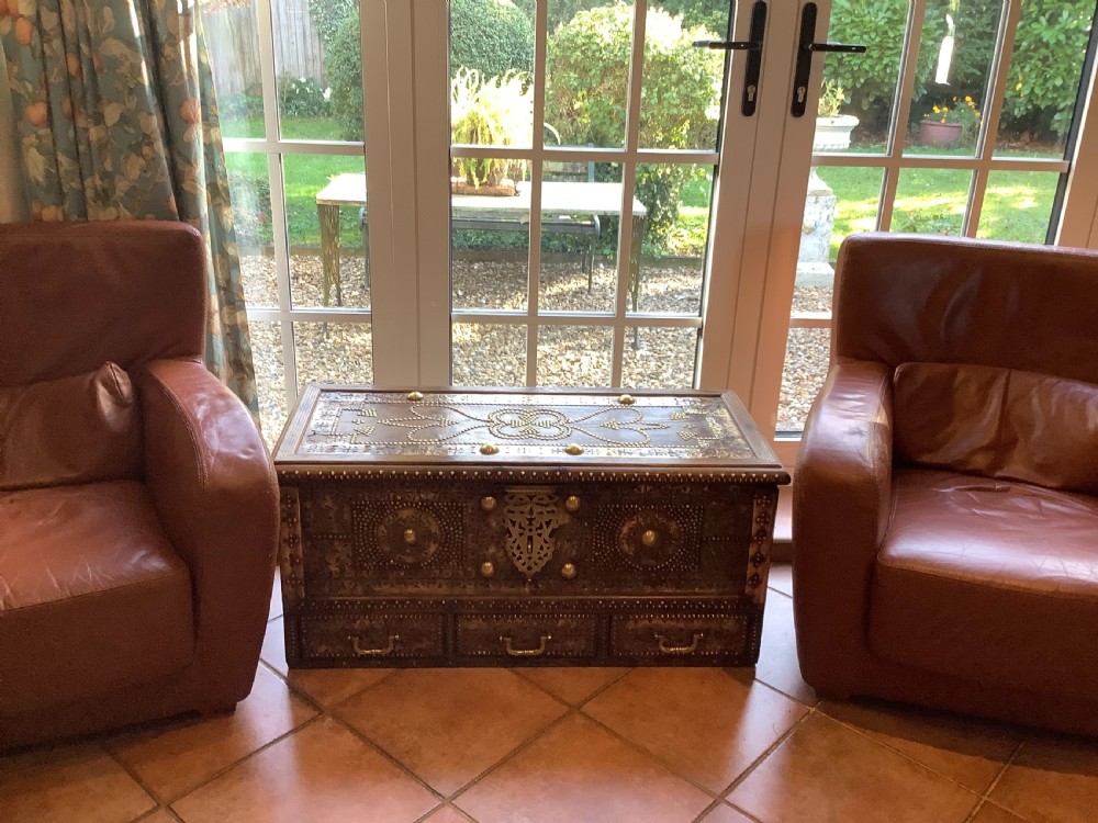 A nineteenth-century wooden Zanzibar storage chest decorated with intricate brass studs, pierced metal plates, three lower drawers, and brass handles. View II