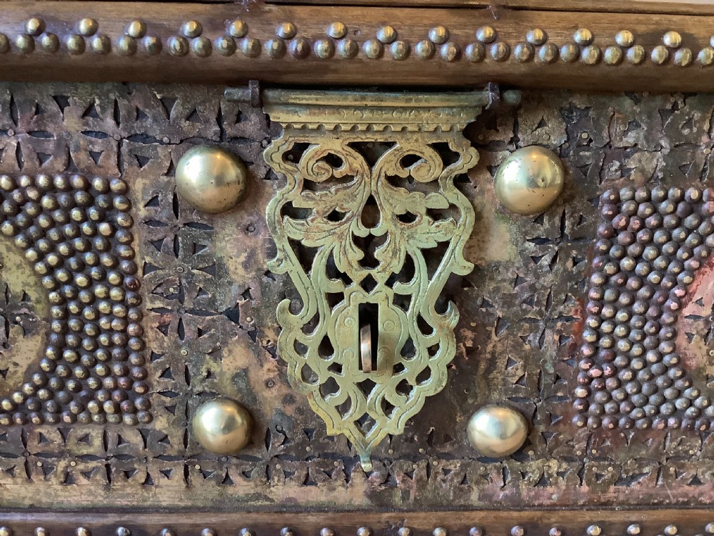 A nineteenth-century wooden Zanzibar storage chest decorated with intricate brass studs, pierced metal plates, three lower drawers, and brass handles. View III