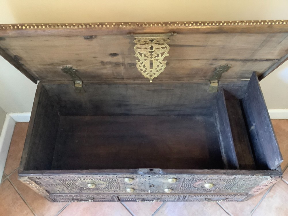 A nineteenth-century wooden Zanzibar storage chest decorated with intricate brass studs, pierced metal plates, three lower drawers, and brass handles. View VII