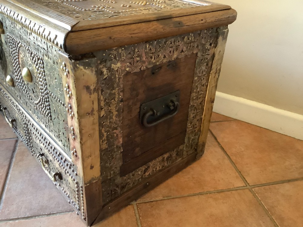 A nineteenth-century wooden Zanzibar storage chest decorated with intricate brass studs, pierced metal plates, three lower drawers, and brass handles. View X