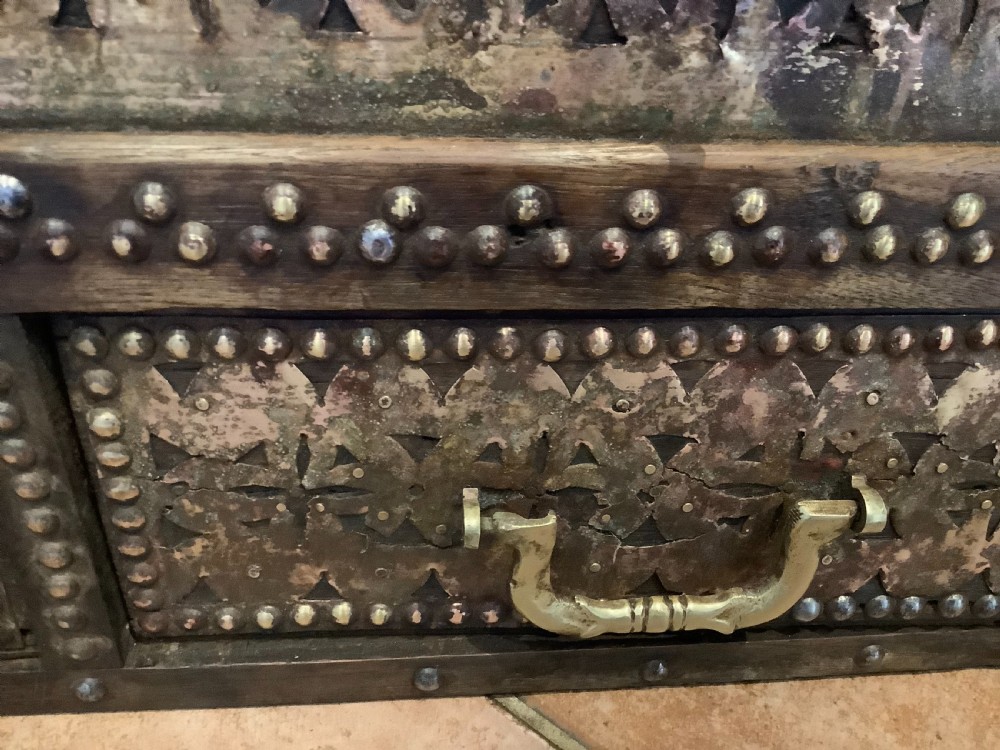 A nineteenth-century wooden Zanzibar storage chest decorated with intricate brass studs, pierced metal plates, three lower drawers, and brass handles. View XIII