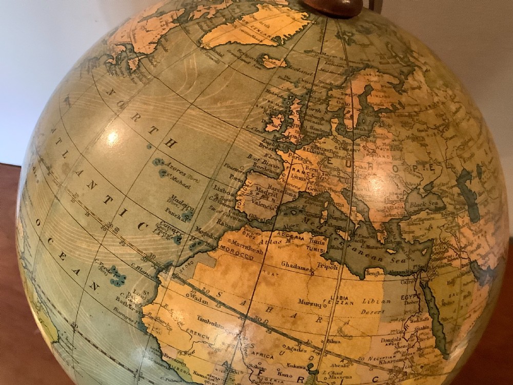 An antique terrestrial desk globe featuring printed paper gores, a brass semi-meridian arc, and a dark turned wooden base. View III