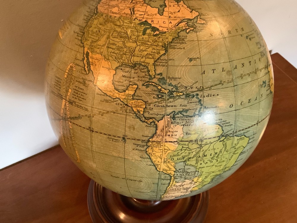 An antique terrestrial desk globe featuring printed paper gores, a brass semi-meridian arc, and a dark turned wooden base. View V
