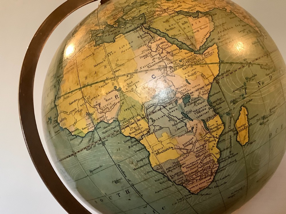 An antique terrestrial desk globe featuring printed paper gores, a brass semi-meridian arc, and a dark turned wooden base. View XII
