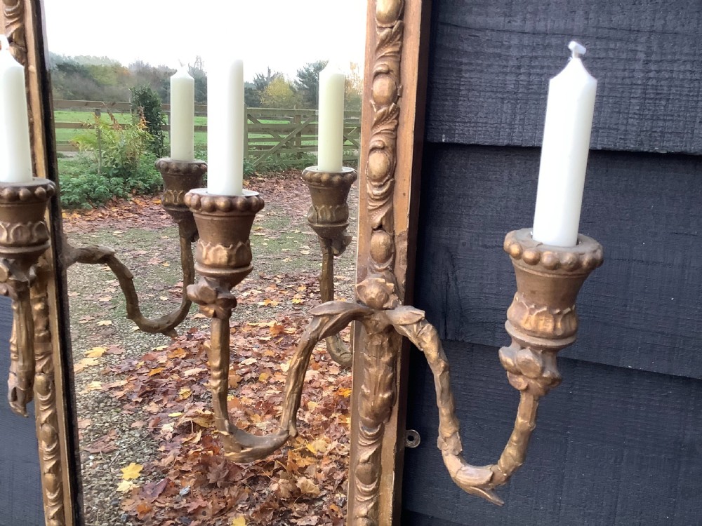 A tall rectangular giltwood pier mirror featuring an arched inner frame, carved classical mouldings, and two attached double-branch candle sconces. View II