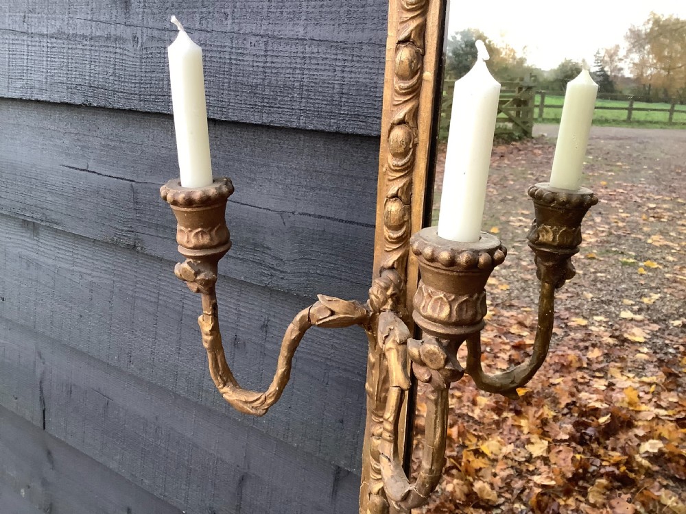 A tall rectangular giltwood pier mirror featuring an arched inner frame, carved classical mouldings, and two attached double-branch candle sconces. View III
