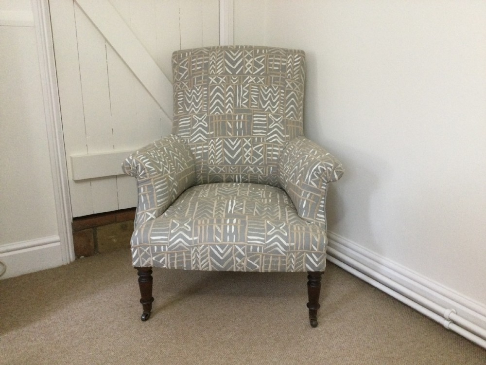 A 19th-century French armchair re-upholstered in a grey and white geometric patterned fabric with dark turned wood front legs on castors.